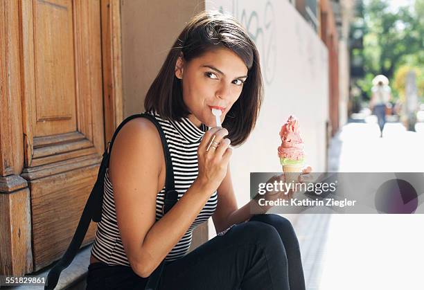 young woman sitting on doorstep, eating ice cream - indulgence stock pictures, royalty-free photos & images