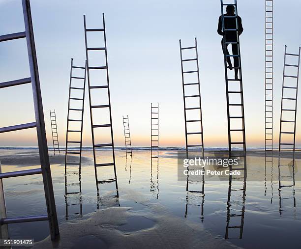business man climbing a ladder,beach ladders - moving up the ladder stock pictures, royalty-free photos & images