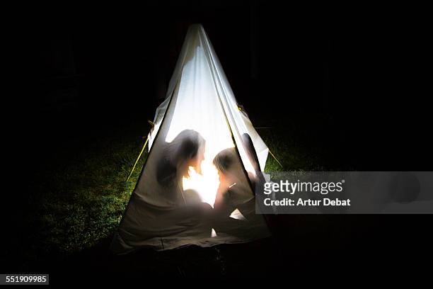 mother telling a story to her son inside tent. - kampeertent stockfoto's en -beelden