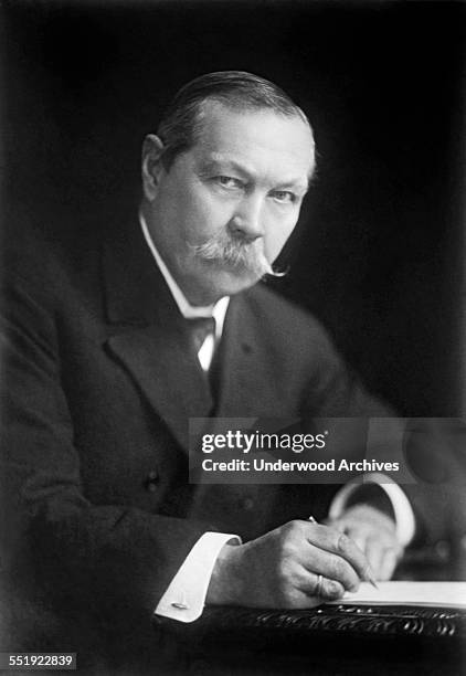 Author Sir Arthur Conan Doyle of the noted Sherlock Holmes series writing at his desk, England, 1923.