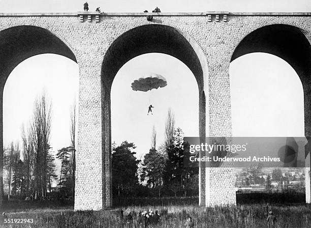 Mademoiselle Bonte makes a dangerous parachute jump of only 87 feet from the viaduct of Palaiseau on the outskirts of Paris while spectators watch...