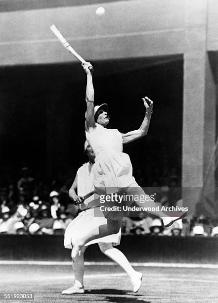 Kea Bouman of the Netherlands leaps high to try to return a high ball in the Doubles quarterfinals at Wimbledon, London, England, 1928. Her partner...