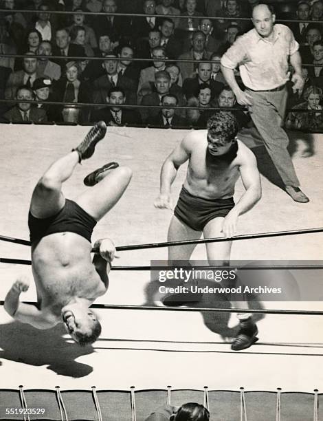 Professional wrestler Al Bisignano checks out his handiwork having just tossed his opponent, Dr Len Hall, over the ropes and nearly out of the ring,...