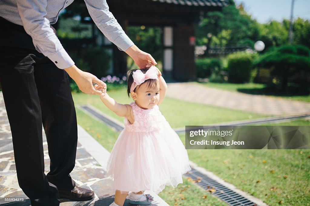 Baby girl learning to walk in garden