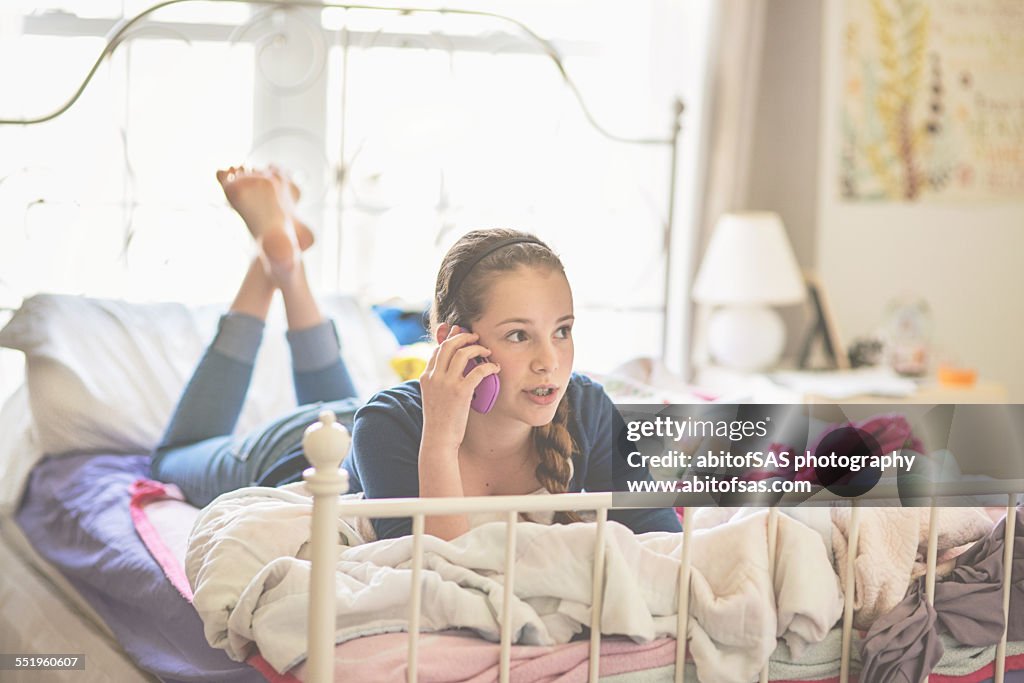 Teen girl laying on bed, talking on phone