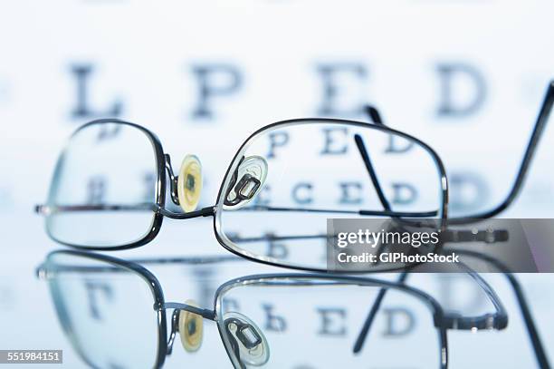 myopic spectacles with a snellen eye chart in the background - ophthalmologist chart stock pictures, royalty-free photos & images