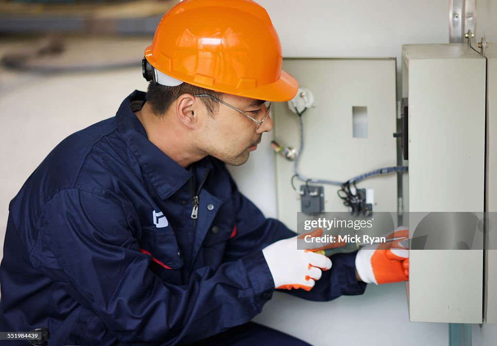 Worker working on fuse box in crane manufacturing facility, China