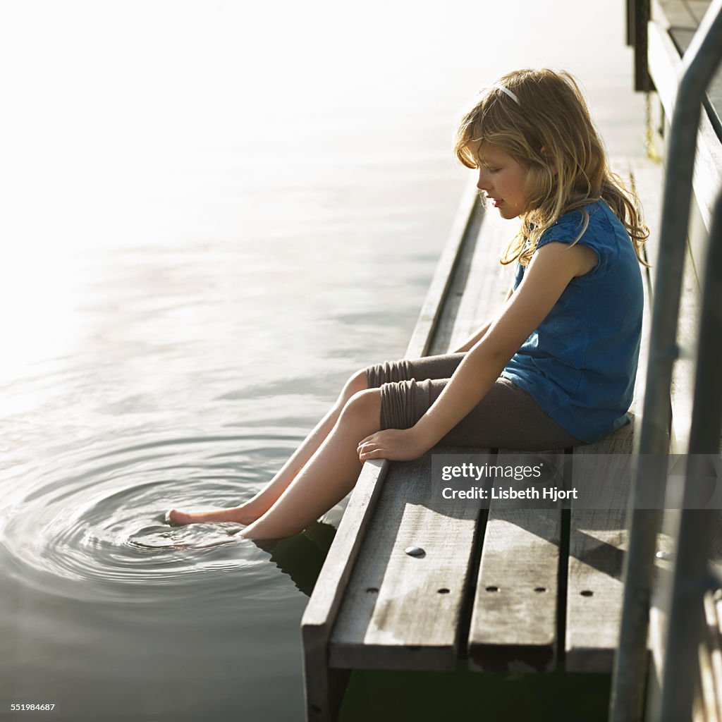Girl dipping feet in lake