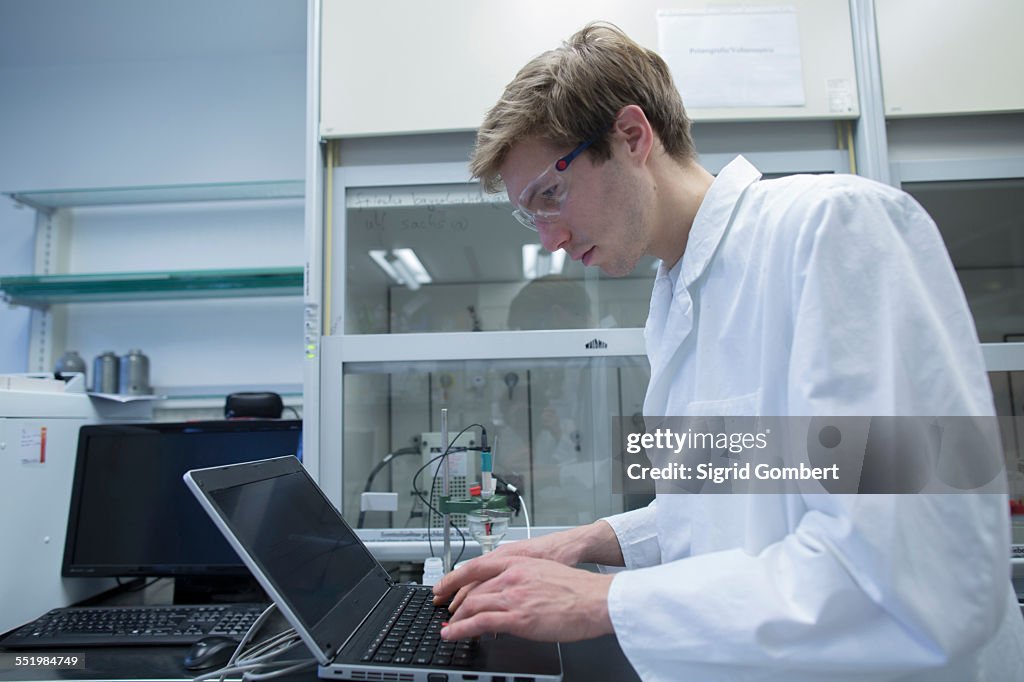 Male scientist typing on laptop in lab