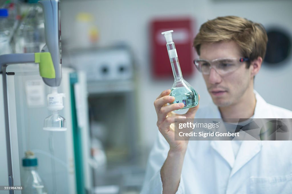 Male scientist looking at flask in lab