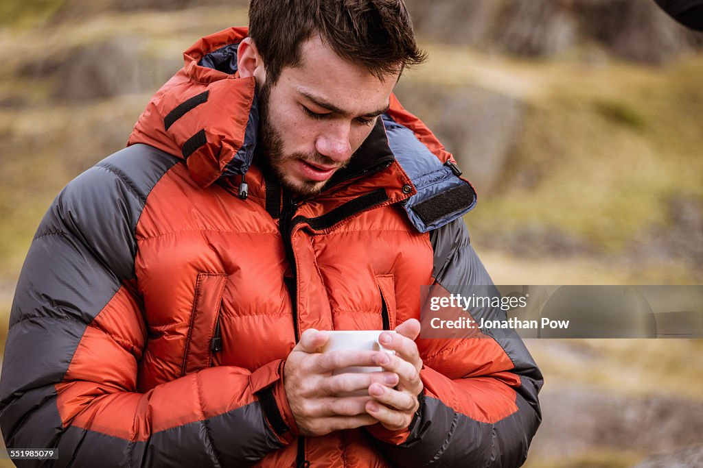 Young male hiker drinking coffee, The Lake District, Cumbria, UK