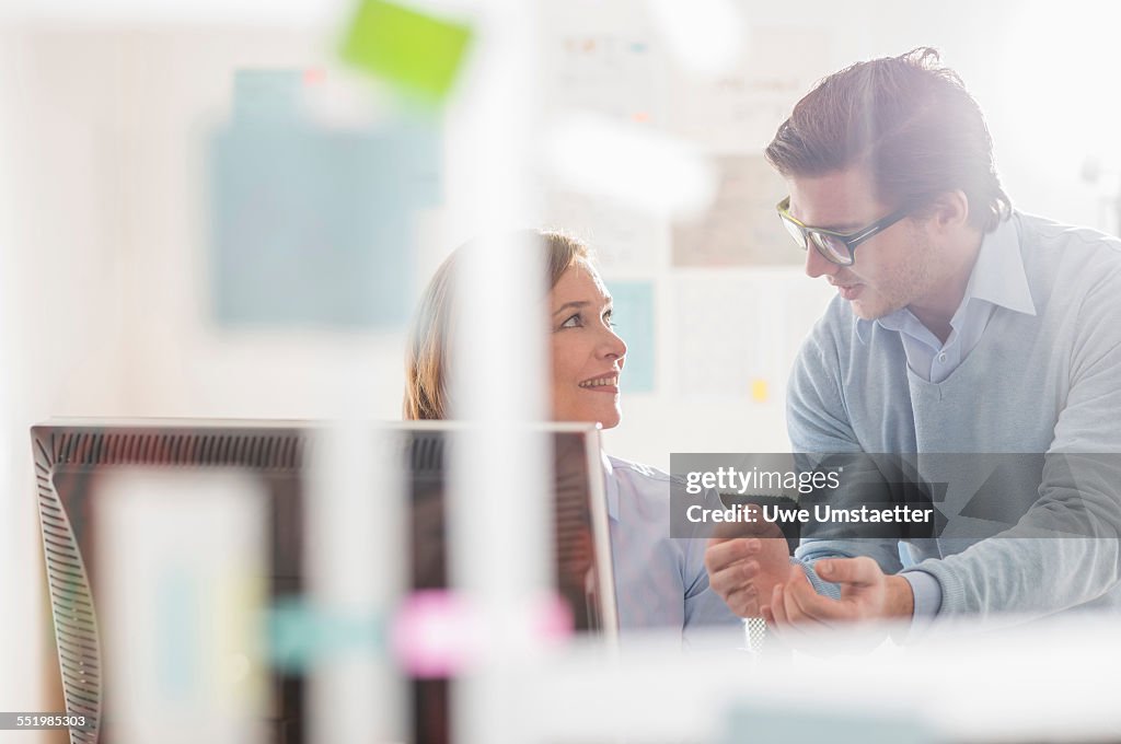 Businessman explaining to female colleague in office