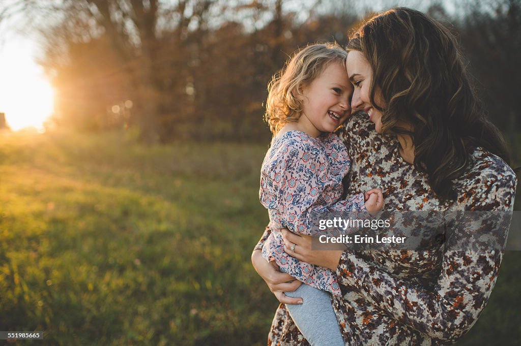 Portrait of young woman carrying daughter in field