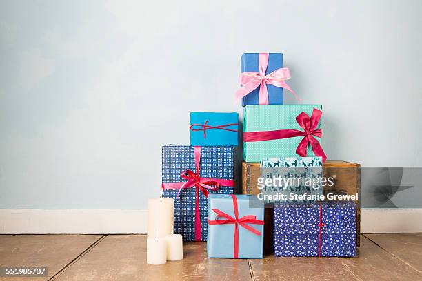 candles and stack of wrapped christmas gifts on wooden floor - christmas gift fotografías e imágenes de stock
