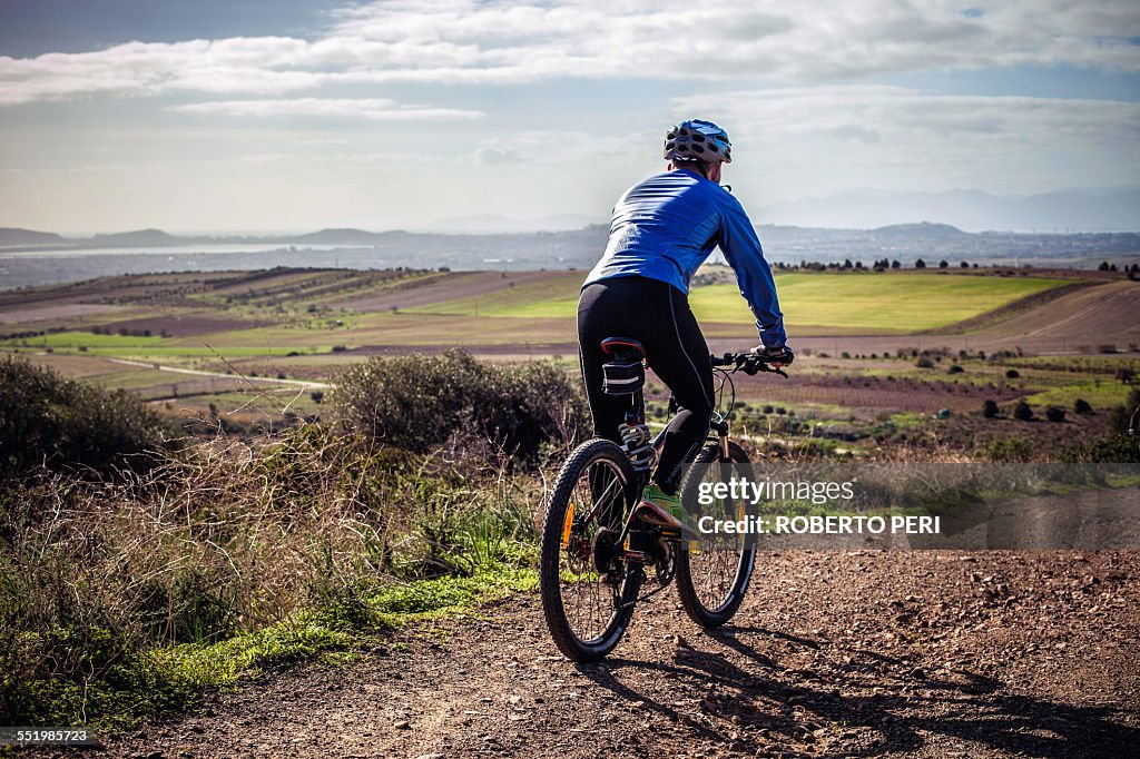 Male mountain biker cycling down dirt track, Cagliari, Sardinia, Italy