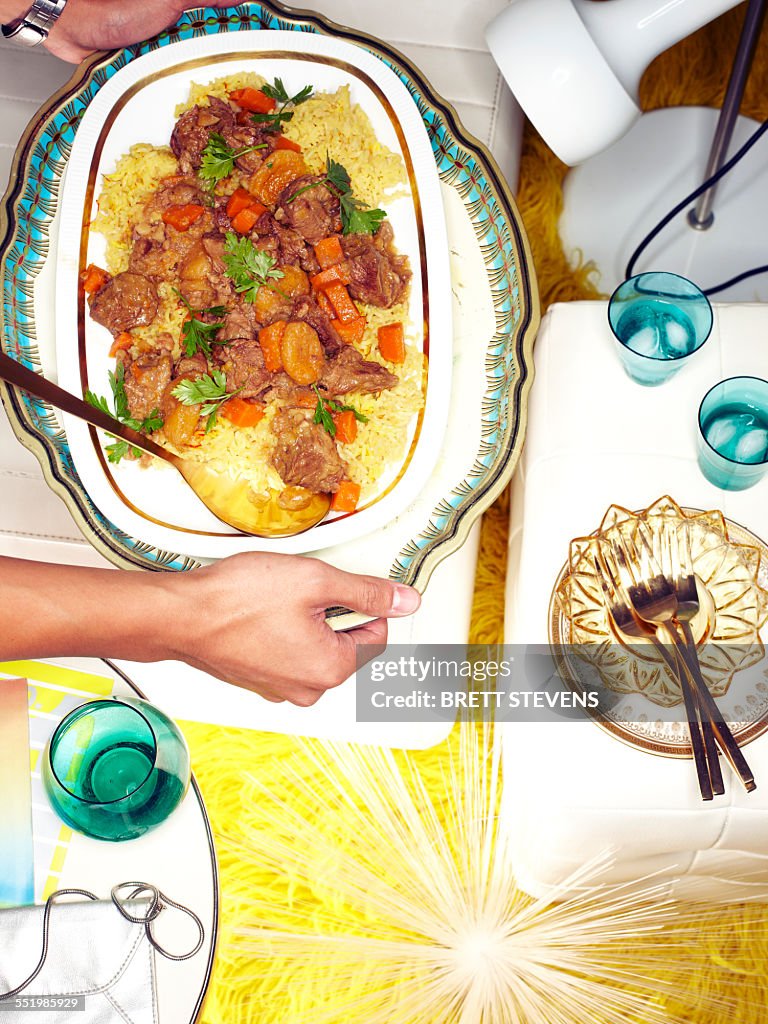 Male hands picking up dish of Azerbaijani plov at retro party