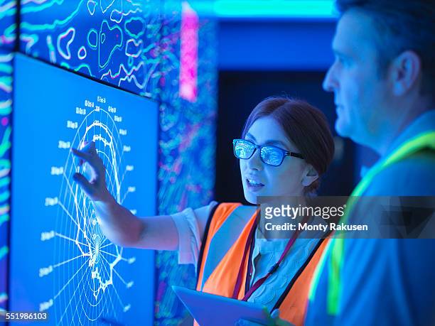female geologist with colleague studying graphical display of oil and gas bearing rock on screens - géologie photos et images de collection