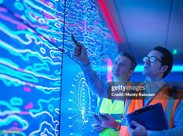 geologists studying graphical display of oil and gas bearing rock on screens - geologie stockfoto's en -beelden