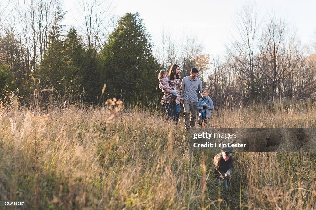 Young couple with son and daughter walking the dog