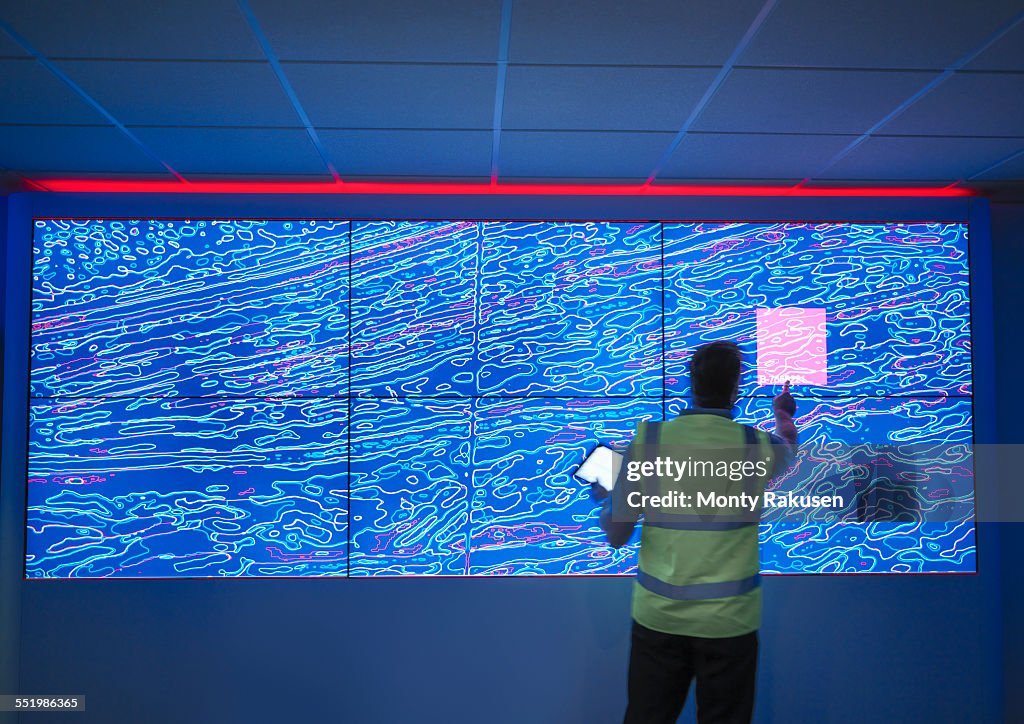 Geologist studying graphical display of oil and gas bearing rock on screens