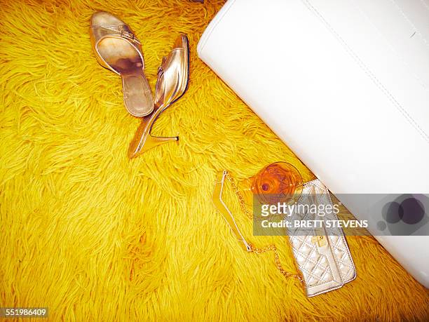 mules, handbag and wine glass on yellow furry rug - hairy stock-fotos und bilder