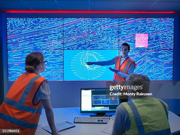 geologists studying graphical display of oil and gas bearing rock on screens - scientist standing next to table stock-fotos und bilder