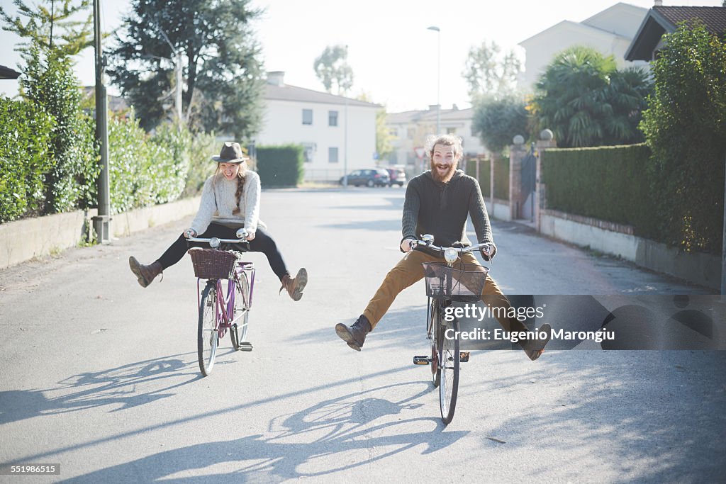 Young couple cycling with legs out