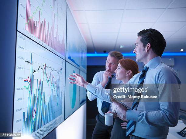 three business people discuss graphs on screen in meeting room - group analysis foto e immagini stock