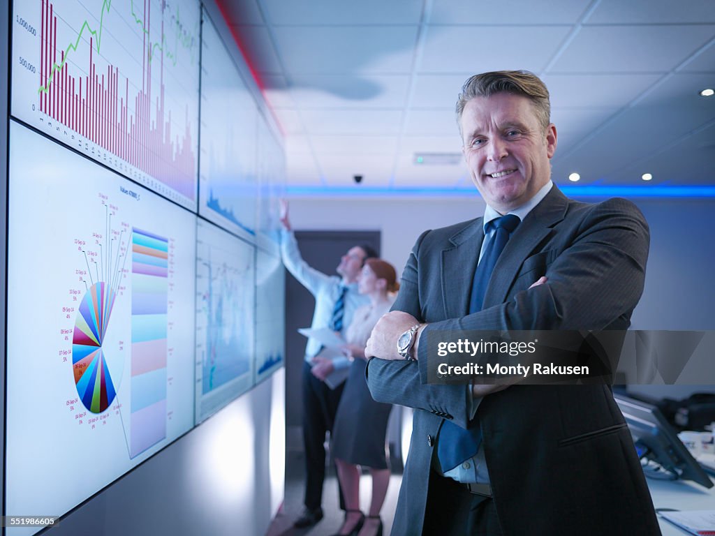 Company manager in front of graphs on screen in meeting room, portrait