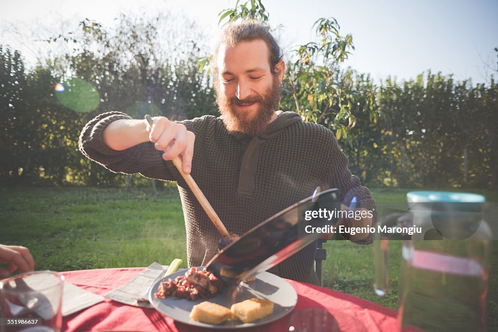 Young man holding frying pan serving food