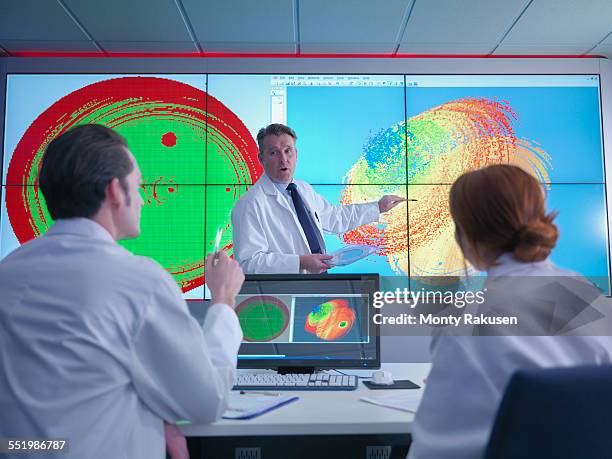 scientists in meeting in front of graphical display of silicon wafer on screens - scientist standing next to table stock pictures, royalty-free photos & images