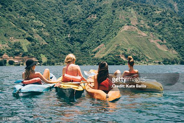 rear view of four young female friends kayaking on lake atitlan, guatemala - sabbatical stockfoto's en -beelden