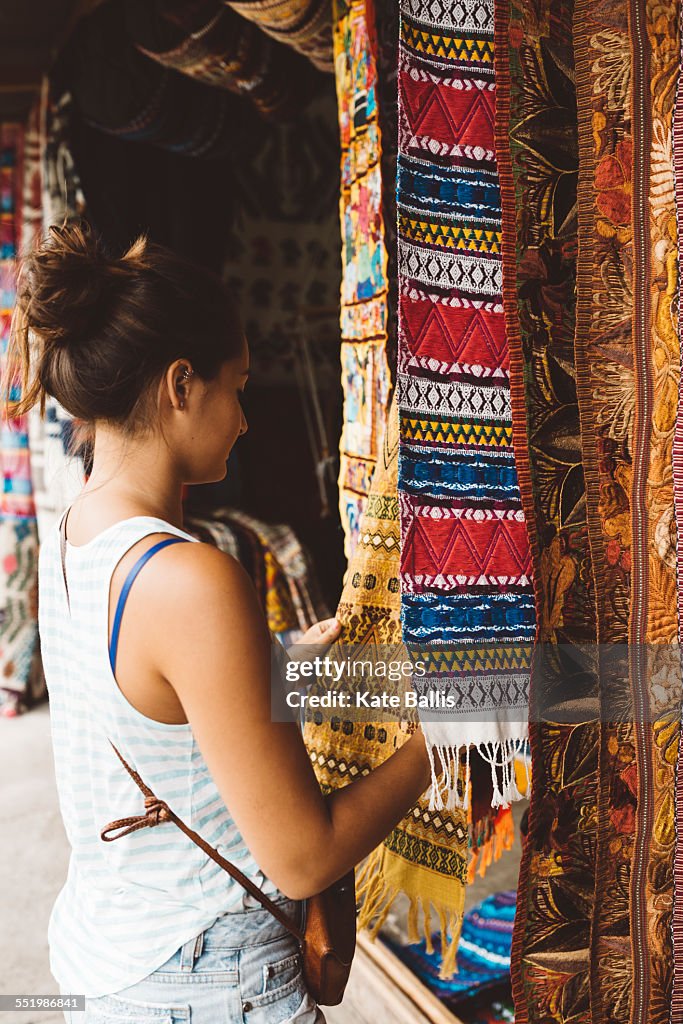 Young woman shopping for textiles at market stall, Lake Atitlan, Guatemala