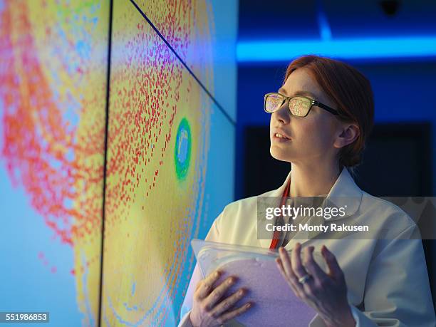 female scientist with silicon wafer studying graphical display of wafer on screens - science and technology foto e immagini stock