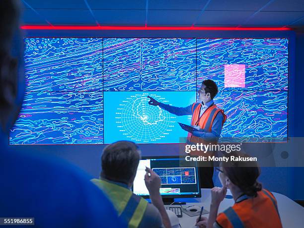 geologists studying graphical display of oil and gas bearing rock on screens - geoloog stockfoto's en -beelden