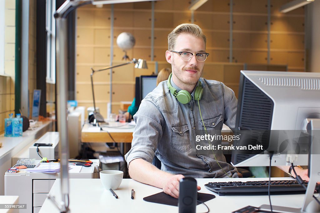 Portrait of young man using computer at office desk