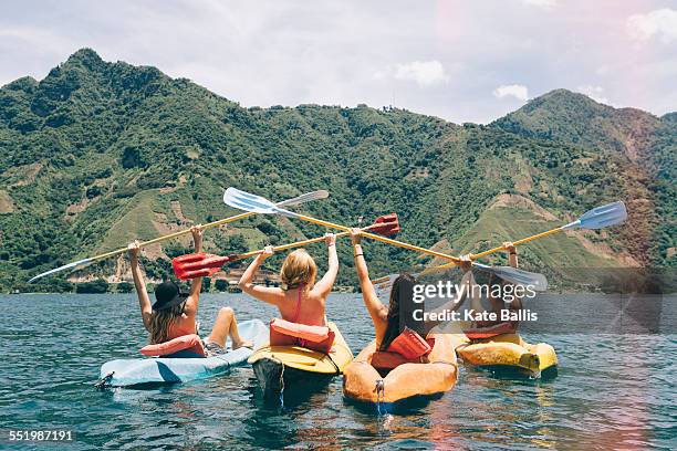 rear view of four female friends celebrating in kayaks on lake atitlan, guatemala - lake atitlan - fotografias e filmes do acervo