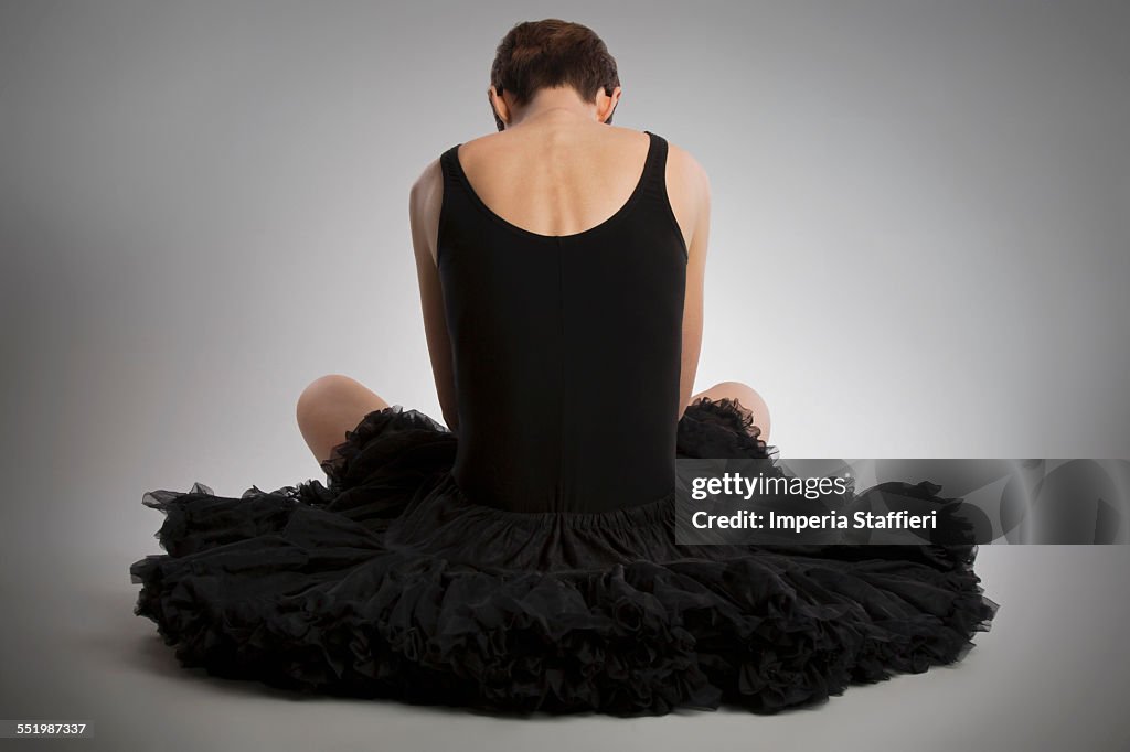 Rear view of woman sitting on floor wearing black tutu