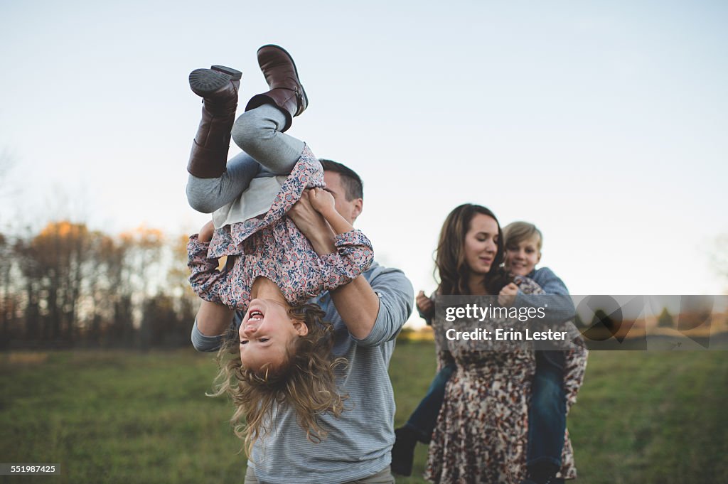 Young couple carrying son and daughter in field