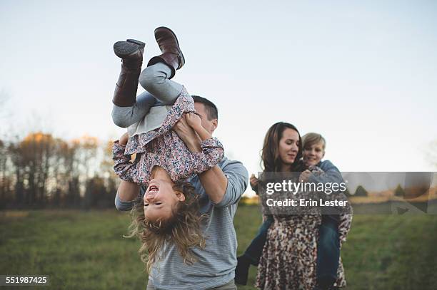 young couple carrying son and daughter in field - rural couple young stockfoto's en -beelden