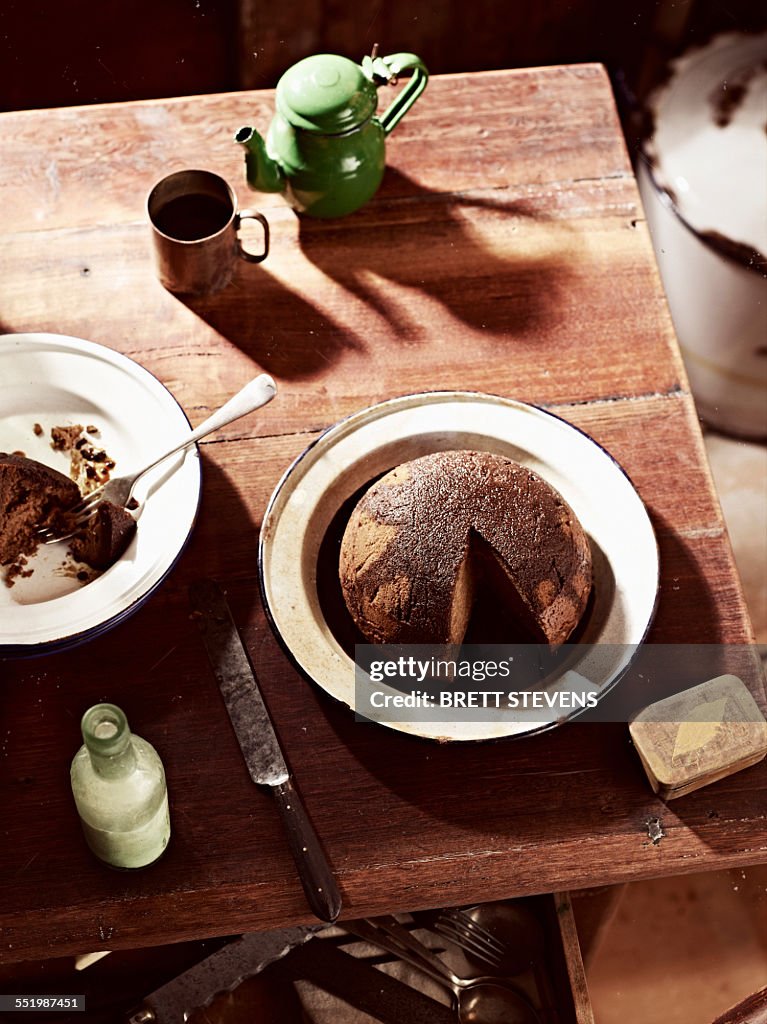 Rustic table with dish of steamed treacle pudding and teapot