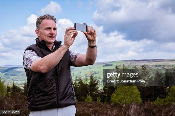 male hiker photographing with smartphone on heather moors, pateley bridge, nidderdale, yorkshire dales - waistcoat stock pictures, royalty-free photos & images