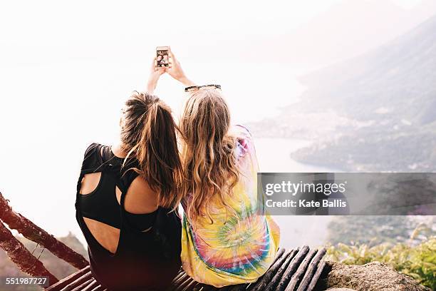 Rear view of two female friends taking smartphone selfie at Lake Atitlan, Guatemala