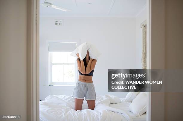 woman on bed with pillow over her head - woman pillow over head stock-fotos und bilder