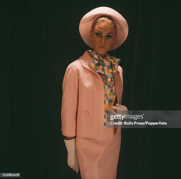 Sixties Fashion - young female model Petrusa Rood wears a peach pink linen suit over a harlequin design silk blouse with large floppy bow at the...