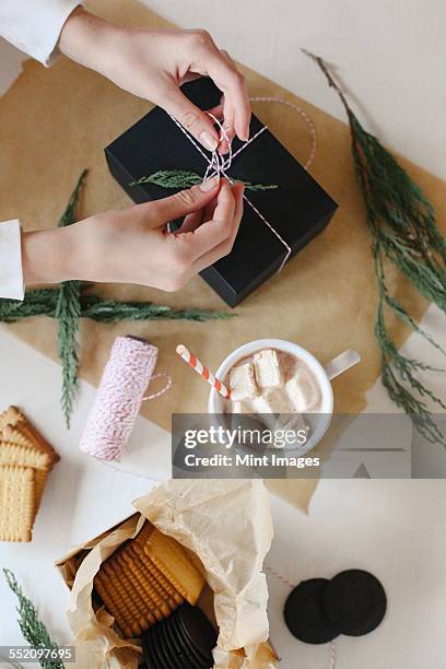 a person wrapping a parcel and a jar of homemade marshmallows. - candy wrapper stockfoto's en -beelden