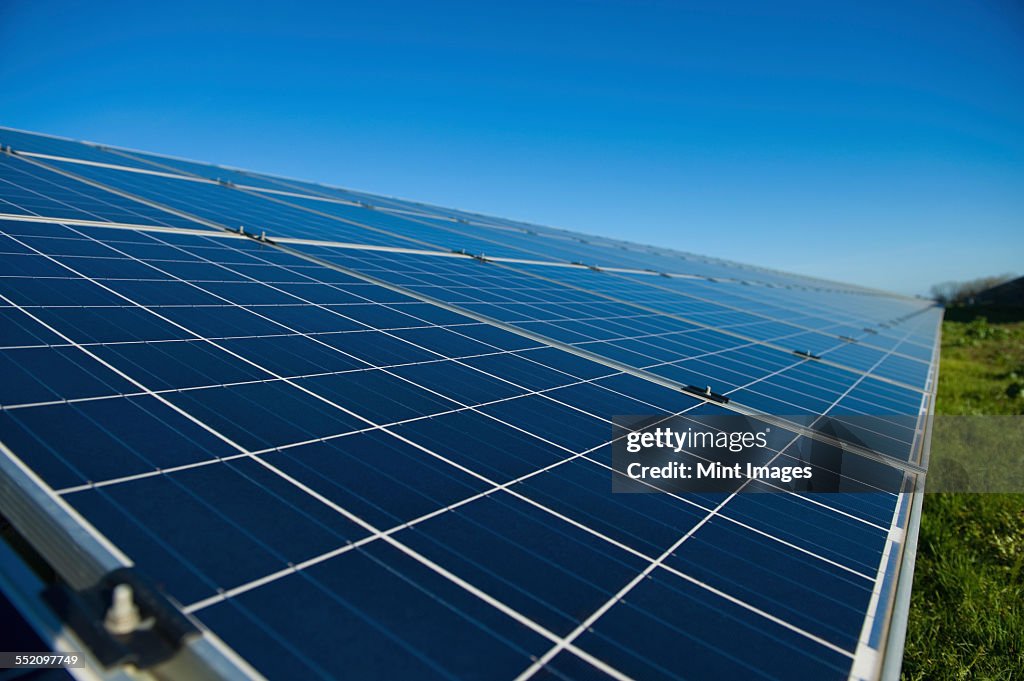 Close up of a row of solar panels in an open field. A solar farm.