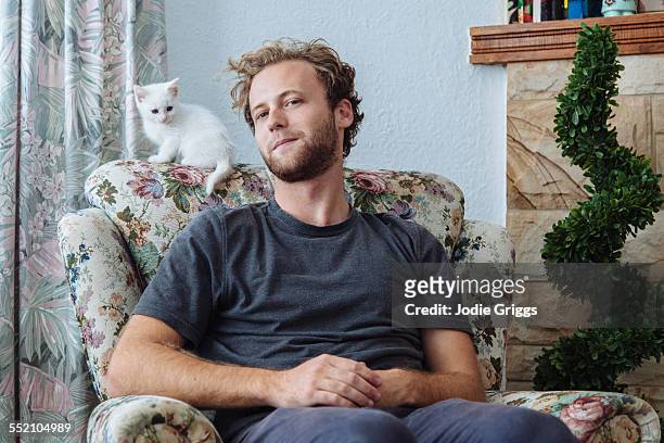 Young man sitting at home with small white kitten
