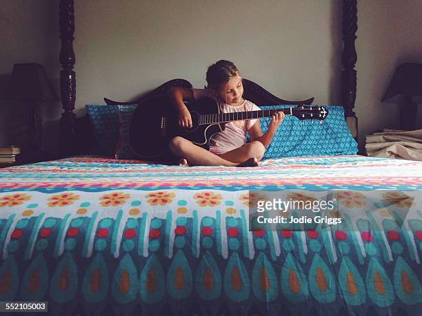 young girl sitting on a bed playing the guitar - chitarra foto e immagini stock