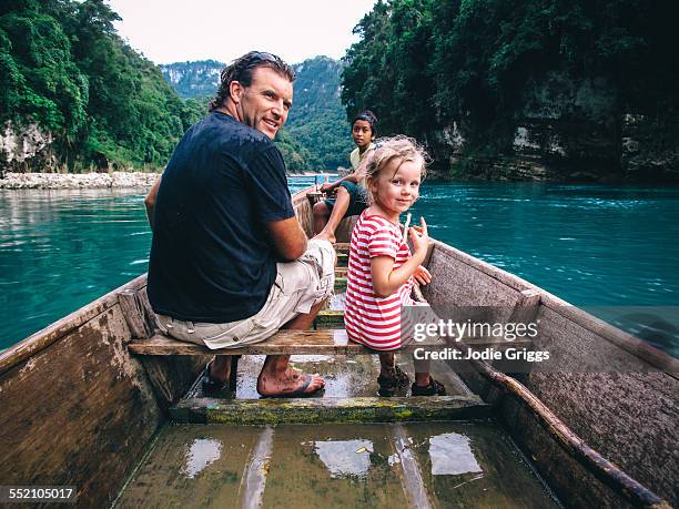 father & child riding in wooden boat down a river - family looking at camera stock pictures, royalty-free photos & images